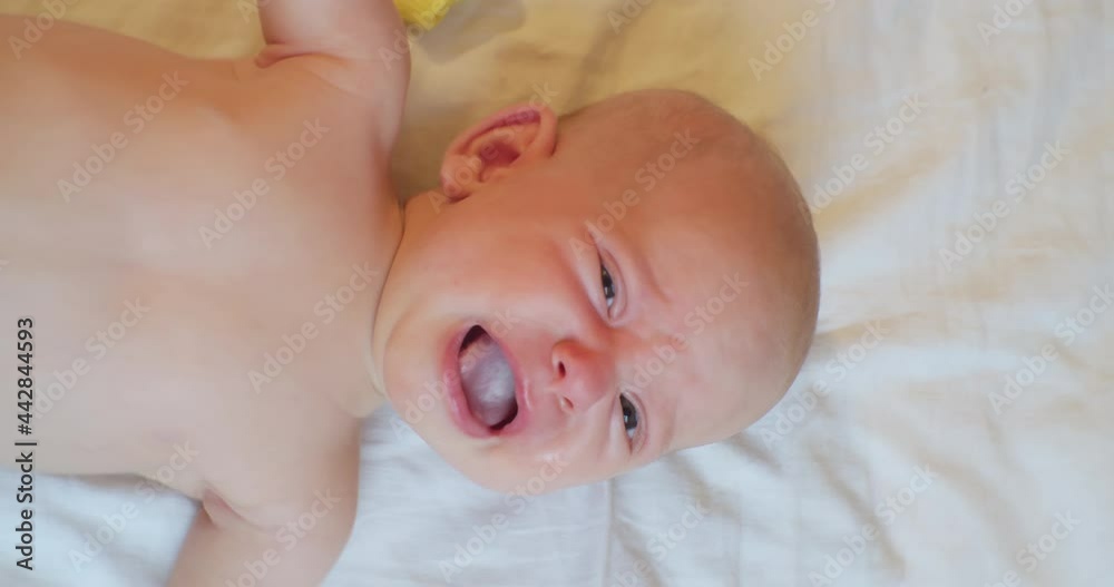 vertical video.portrait of a modern child.cute baby infant crying lying in bed. view from above. vertical video.portrait of a modern child.cute baby infant crying lying in bed. view from above.