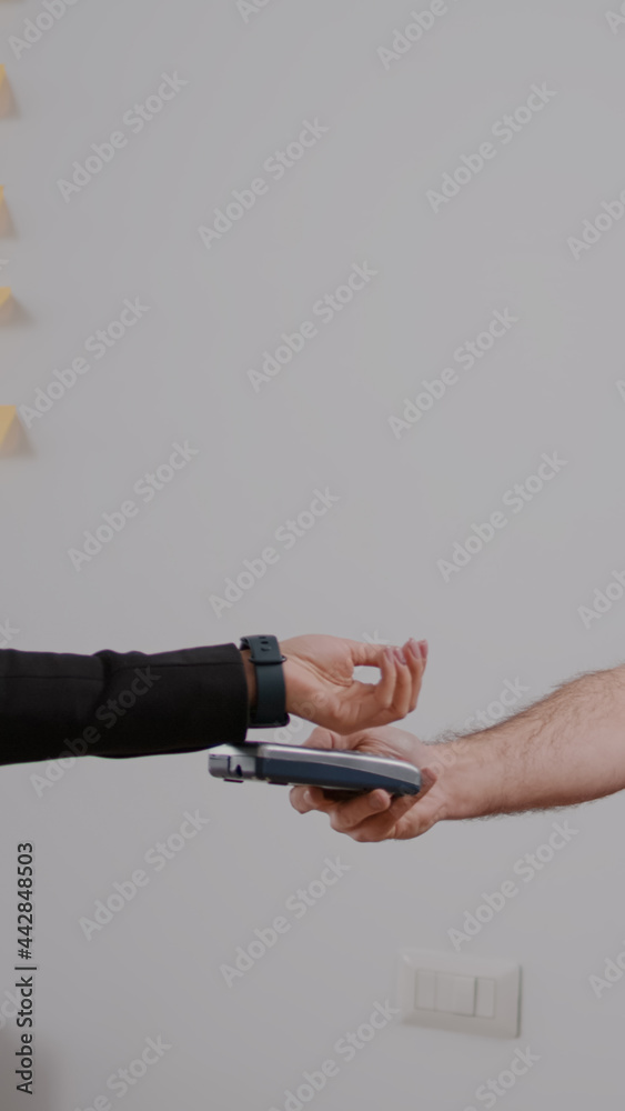 Fototapeta premium Delivery guy with protection face mask and gloves delivering takeaway food box during lunchtime in company office. Businesswoman client paying meal order with smart watch using POS contactless
