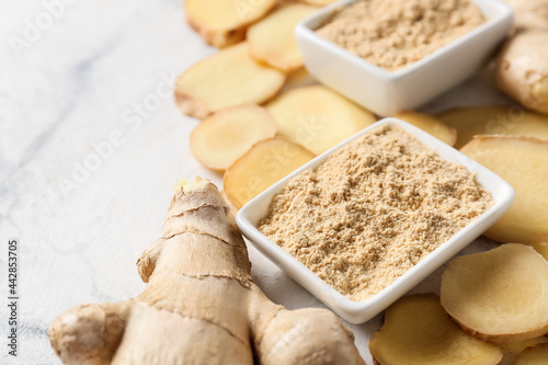 Ginger powder and fresh roots on light background, closeup