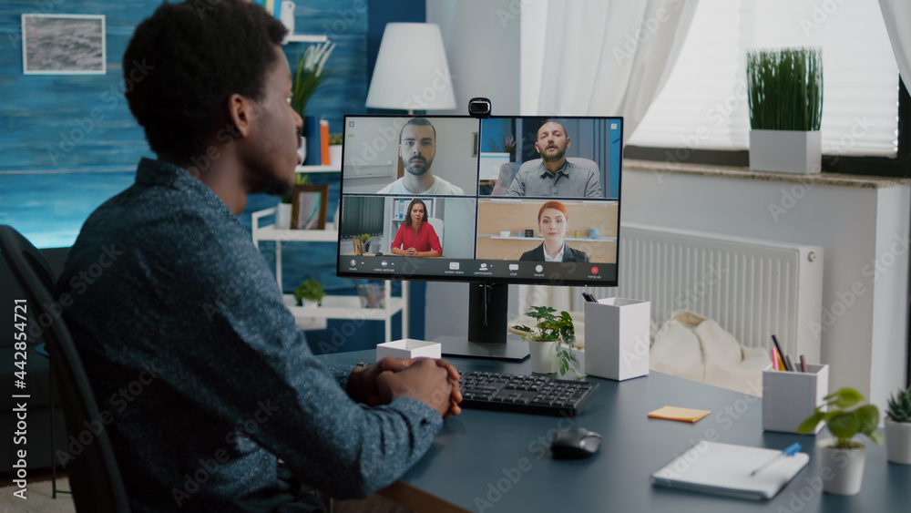 Black man on online internet conference chat with his coworkers, remote working from home, using teleconference web communication with webcam. Distance technology talking Black man on online internet conference chat with his coworkers, remote working from home, using teleconference web communication with webcam. Distance technology talking