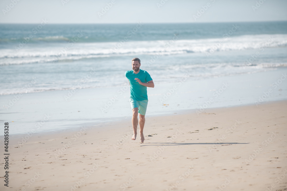 Morning jogging on a sandy beach near sea or ocean. Man running on beach.