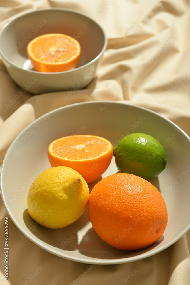 Bowls with healthy citrus fruits on light fabric background Bowls with healthy citrus fruits on light fabric background
