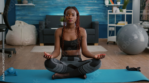 Flexible flexible athlete woman relaxing in lotus position on floor in living room enjoying healthy lifestyles. Fitness woman in sportwear streching muscle during morning gymnastics