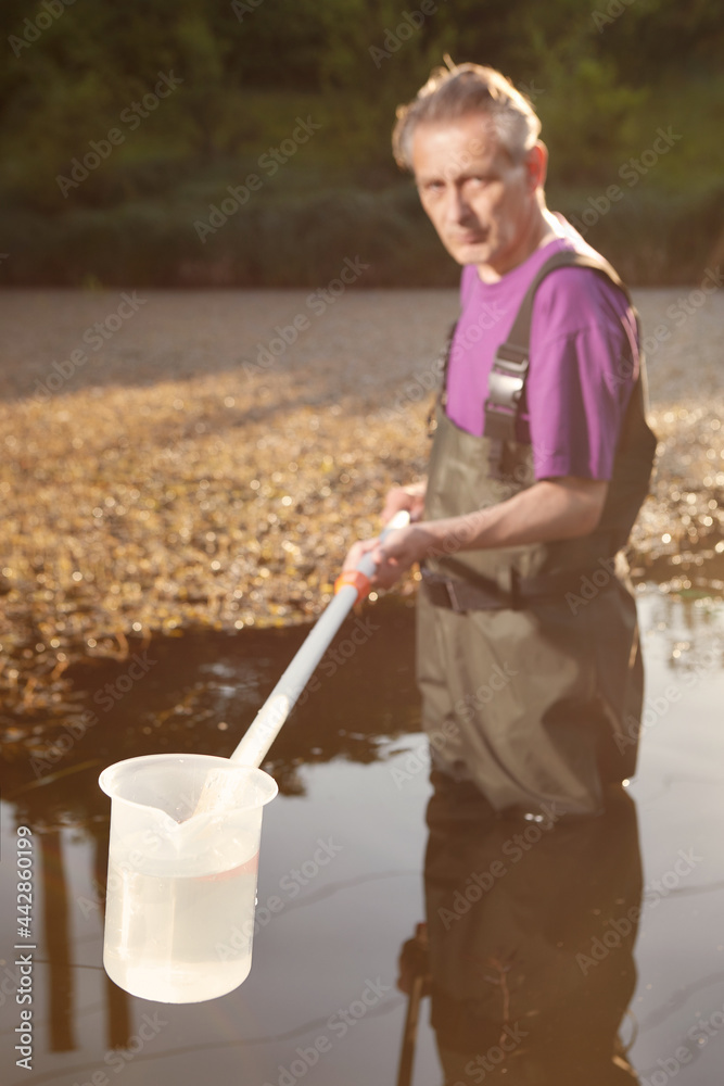 Water quality analyst dressed in chest wader collecting samples Water quality analyst dressed in chest wader collecting samples