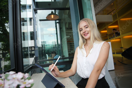 Free Download Young and cheerful woman working on digital tablet using wireless internet while sitting relaxed at cafe. Concept of leisure, freelance and mobile work - GFXLoad
