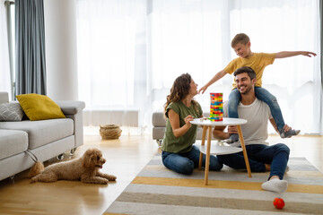 Happy family having fun time, playing together at home with dog