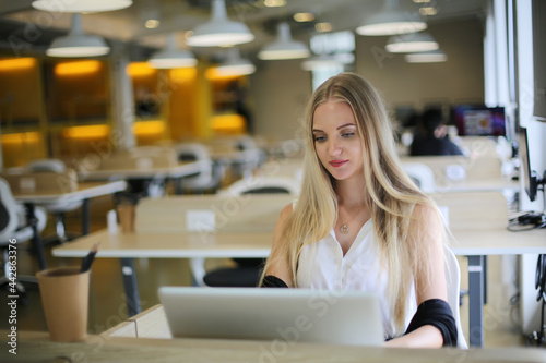 Smiling woman using laptop in work place for small businesses looking to engage audiences and scale content creation can adopt new marketing technology in workspace. Freelancer concept. © FotoArtist
