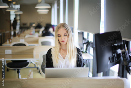 Smiling woman using laptop in work place for small businesses looking to engage audiences and scale content creation can adopt new marketing technology in workspace. Freelancer concept.