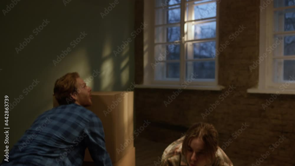 Joyful couple relocating in new apartment. Man hugging woman in renewed room. Joyful couple relocating in new apartment. Man hugging woman in renewed room.