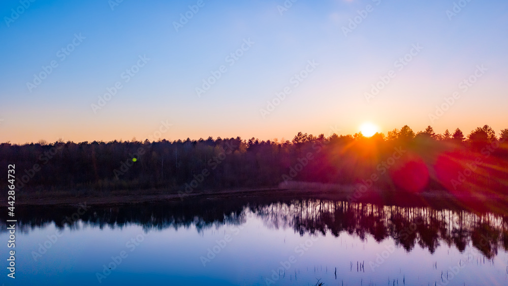 Aerial view of a beautiful and dramatic sunset over a forest lake reflected in the water, landscape drone shot. Blakheide, Beerse, Belgium. High quality photo Aerial view of a beautiful and dramatic sunset over a forest lake reflected in the water, landscape drone shot. Blakheide, Beerse, Belgium. High quality photo