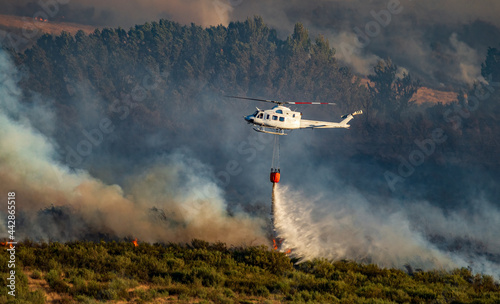 Helicopter with bambi bucket throwing water to flames photo