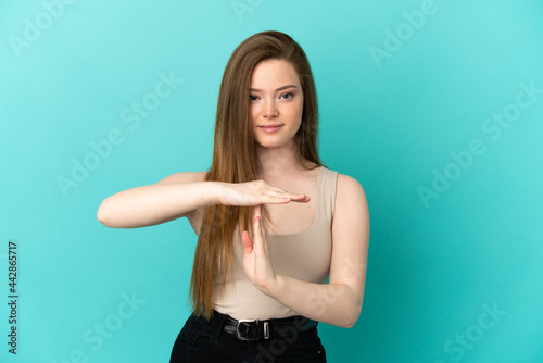 Teenager girl over isolated blue background making time out gesture © luismolinero