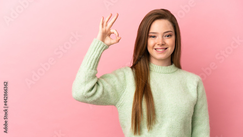 Teenager girl over isolated pink background showing ok sign with fingers