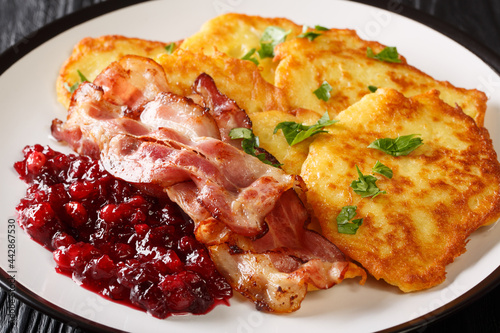 Foto Scandinavian potato pancakes served with lingonberry jam and bacon close-up on a plate on the table