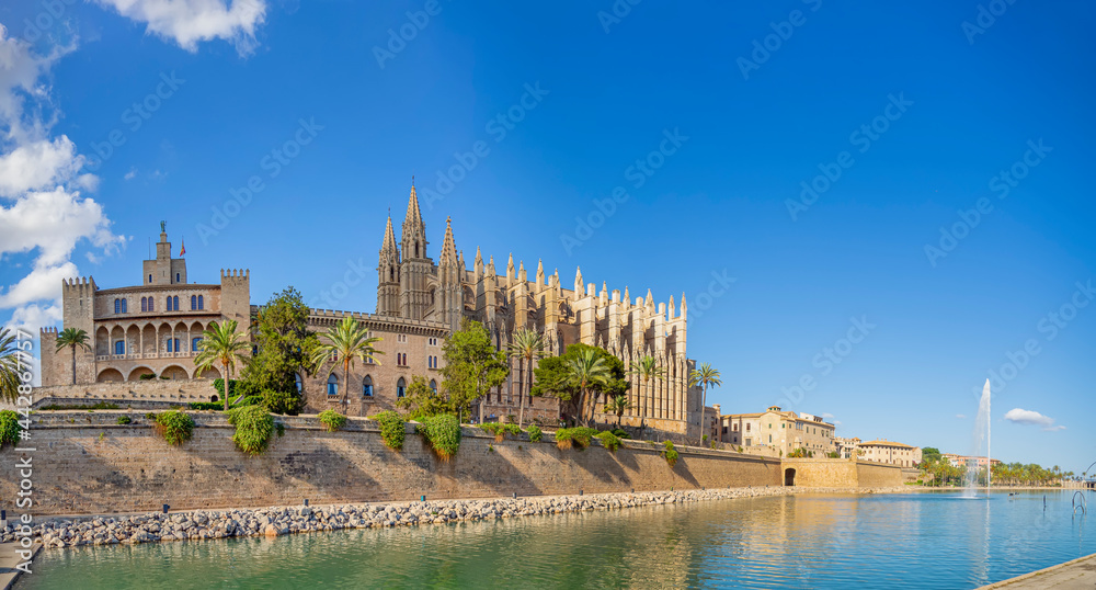 Panoramic of Cathedral of Palma de Majorca and La Almudaina Palace with a fountain in the fortress. Tourist and historic landmark of Mallorca island. Gothic-style monument. Spanish travel destination