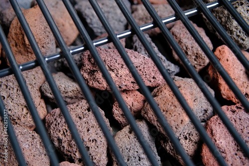 Lava stone for grilling. The view through the blurred grill grate. Close-up. Selective focus.