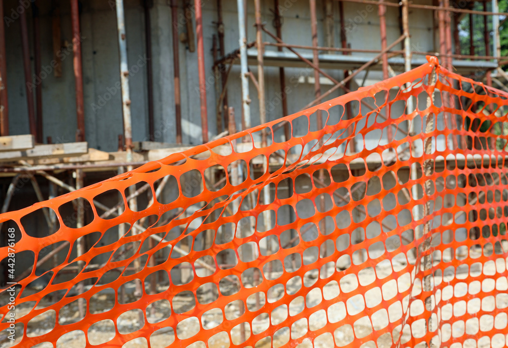 orange plastic net for the protection of the construction site during the renovation of a building with materials for energy saving