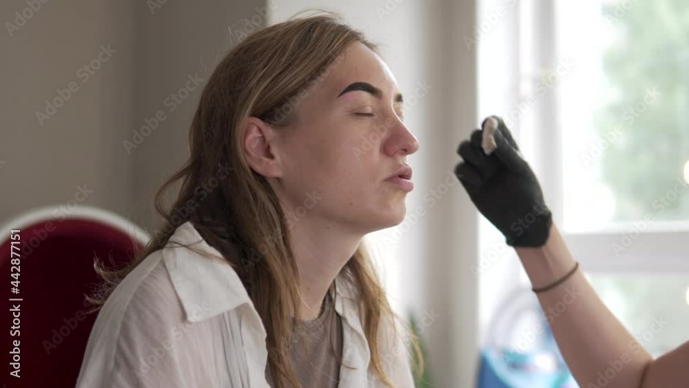 Coring and painting eyebrows in the beauty salon, close-up of the client's face with paint on the eyebrows. Coring and painting eyebrows in the beauty salon, close-up of the client's face with paint on the eyebrows.