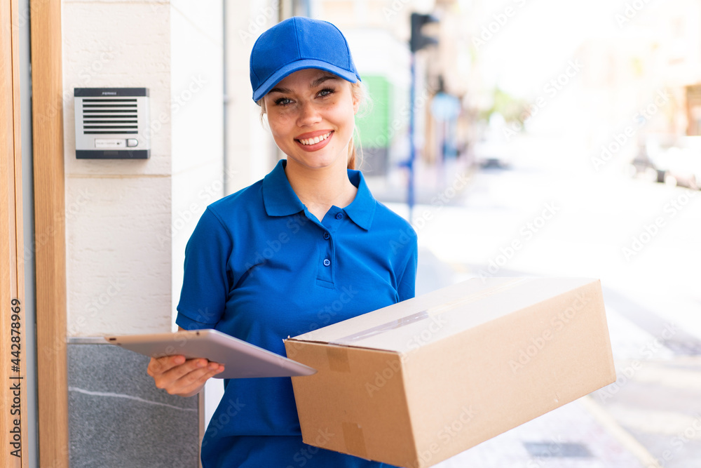 Young delivery woman at outdoors holding boxes and a tablet with happy expression Young delivery woman at outdoors holding boxes and a tablet with happy expression