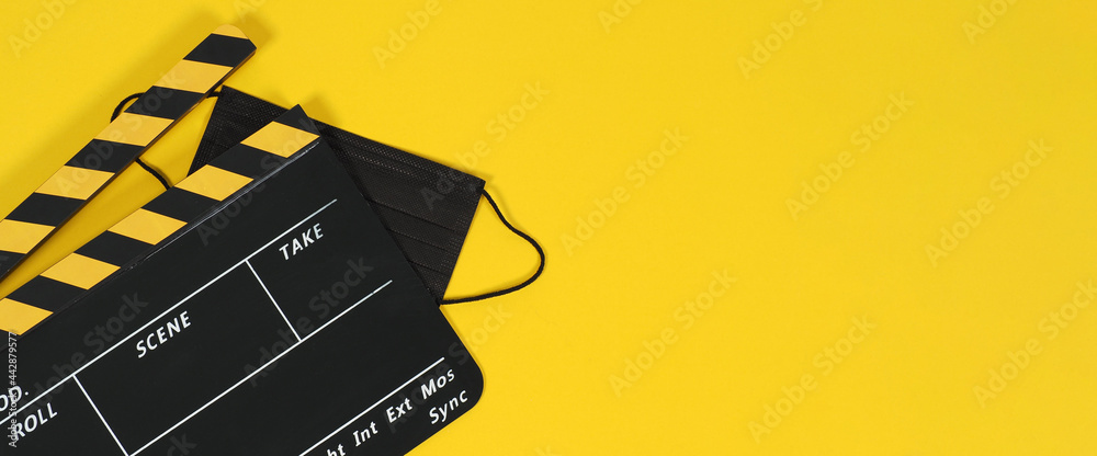 Clapper board or movie slate and black face mask on yellow blackground. Yellow and black color.