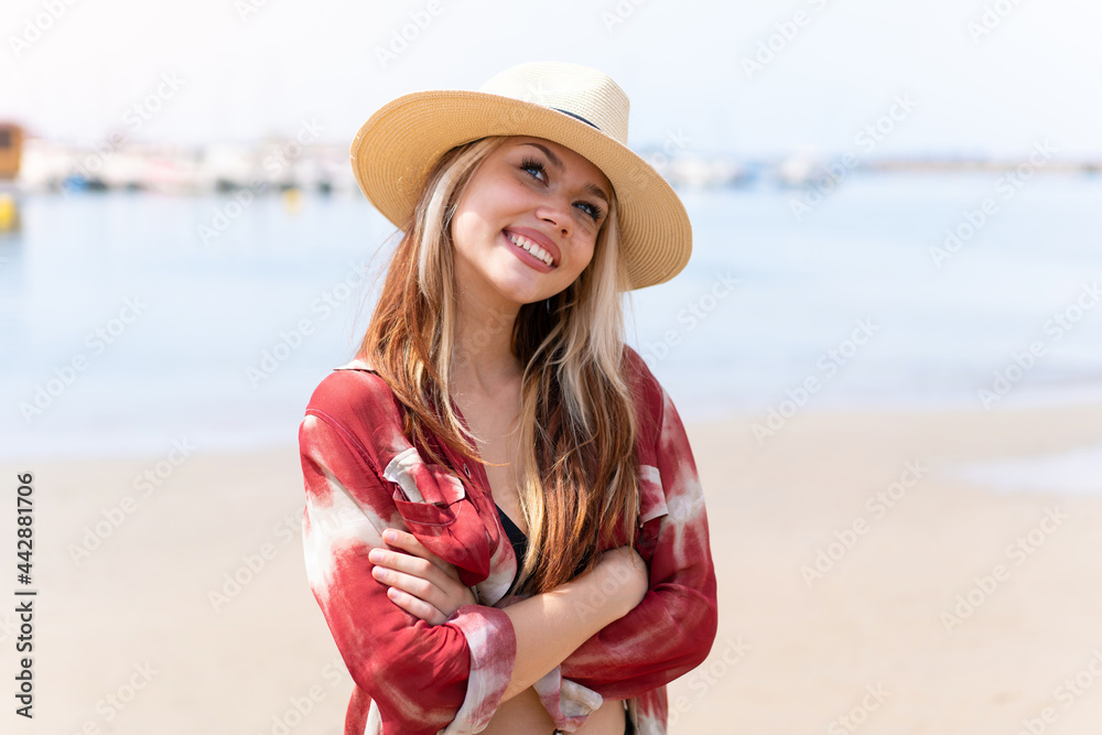 Young pretty woman in summer holidays at beach looking up while smiling