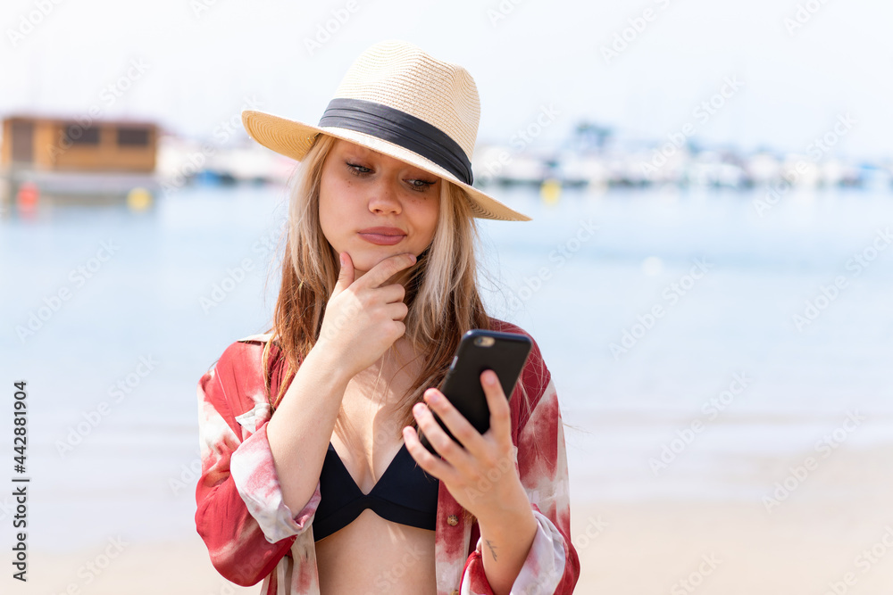 Young pretty woman in summer holidays at beach thinking and sending a message
