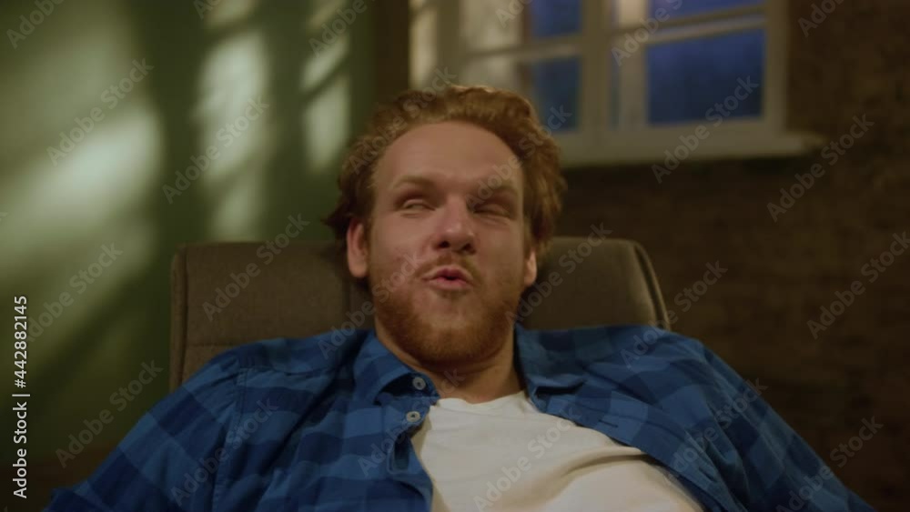 Joyful man relaxing in new apartment. Smiling guy falling into armchair. Joyful man relaxing in new apartment. Smiling guy falling into armchair.