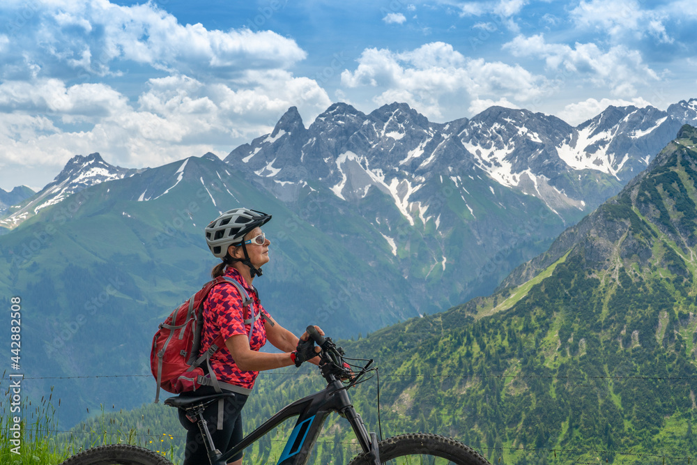 nice senior woman on mountain bike climbing up Mount Fellhorn in the Allgaeu High Alps with Trettach and Maedelegabel in background, Allgau, Bavaria, Germany nice senior woman on mountain bike climbing up Mount Fellhorn in the Allgaeu High Alps with Trettach and Maedelegabel in background, Allgau, Bavaria, Germany