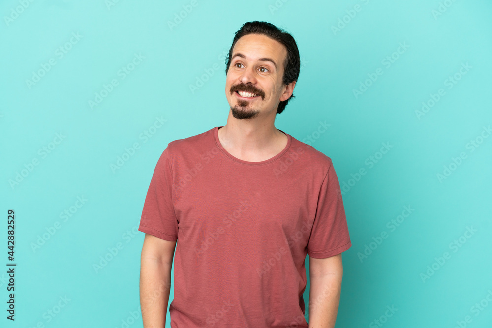 Young caucasian man isolated on blue background thinking an idea while looking up Young caucasian man isolated on blue background thinking an idea while looking up