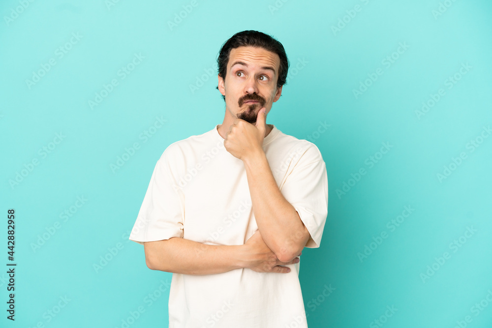 Young caucasian man isolated on blue background having doubts Young caucasian man isolated on blue background having doubts