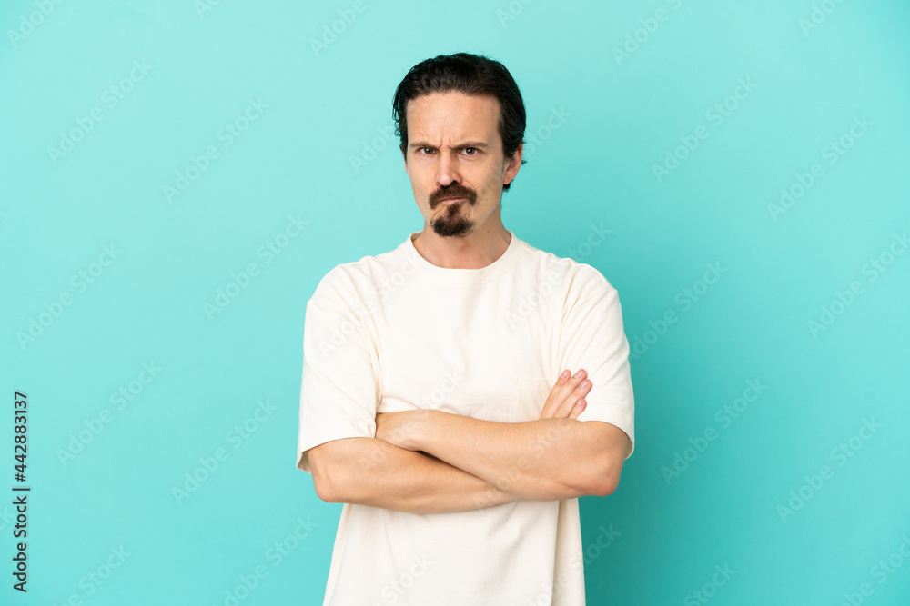 Young caucasian man isolated on blue background with unhappy expression Young caucasian man isolated on blue background with unhappy expression