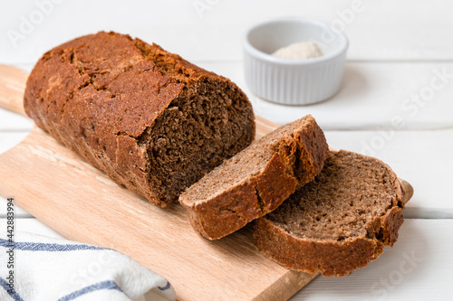 Freshly baked rye bread sliced on wooden board. Light wooden background with copy space.