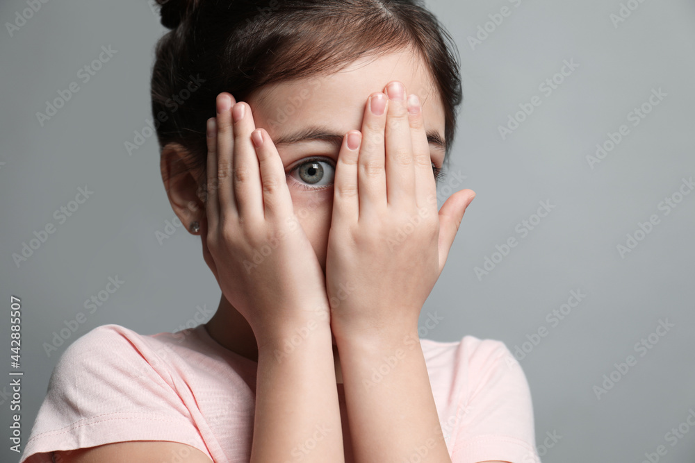 Little girl feeling fear on grey background, closeup Little girl feeling fear on grey background, closeup