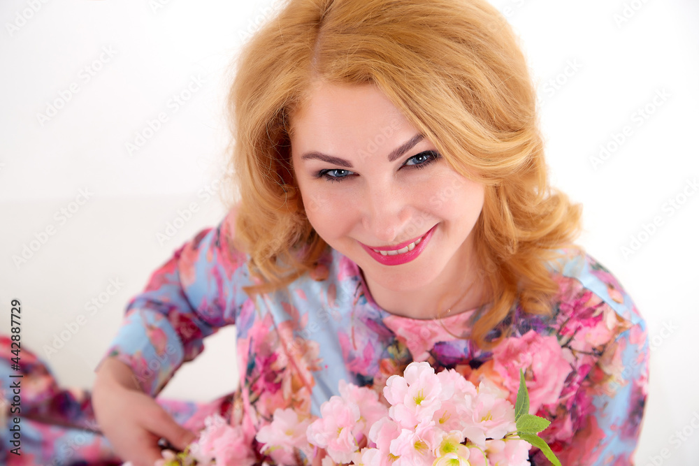 Happy beautiful woman with long blond curly hair posing with flowers in studio on white background Happy beautiful woman with long blond curly hair posing with flowers in studio on white background