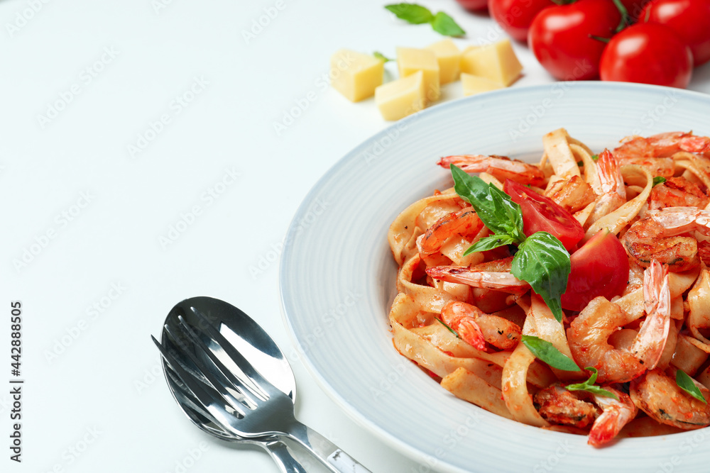 Plate of shrimp pasta and ingredients on white background