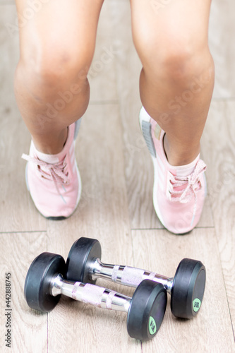 A legs of a training woman with steel dumbbells lying on the floor.