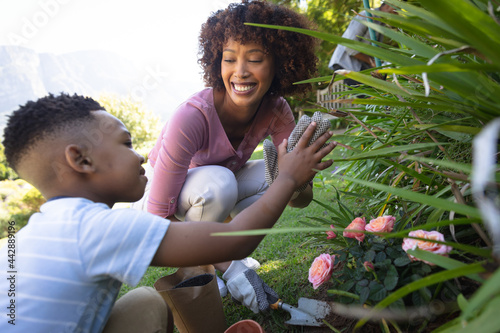Happy african american mother with son outdoors, gardening on sunny day