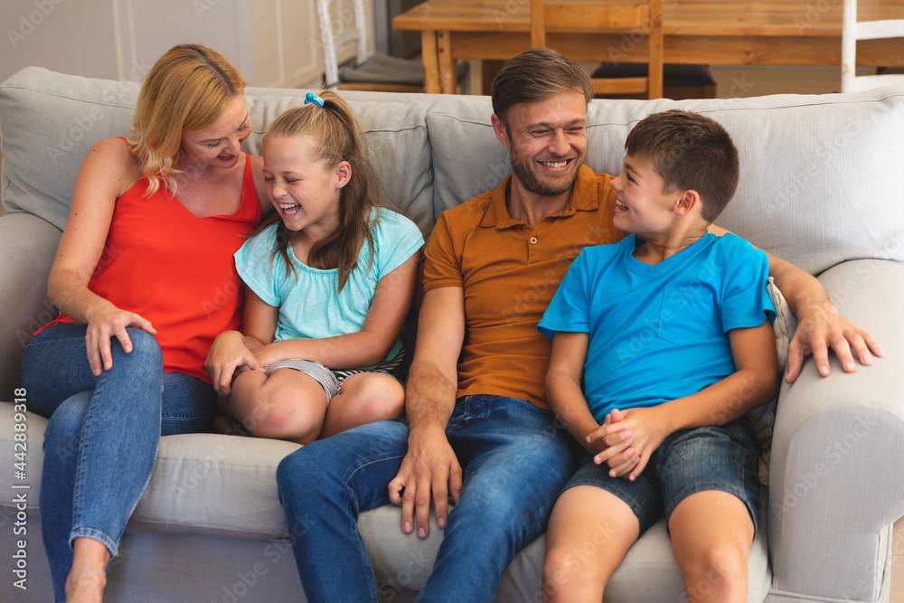 Caucasian couple with daughter and son sitting on couch and smiling at home
