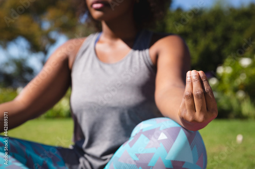 Midsection of african american woman practicing yoga in sunny garden