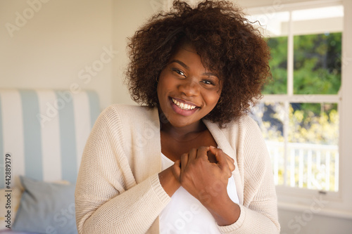 Portrait of smiling african american woman sitting on bed at home