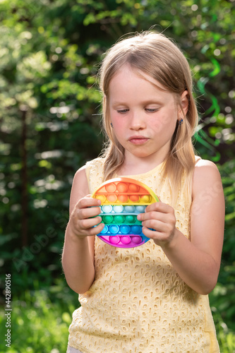 Сhild plays push pop bubble fidget toy outdoors