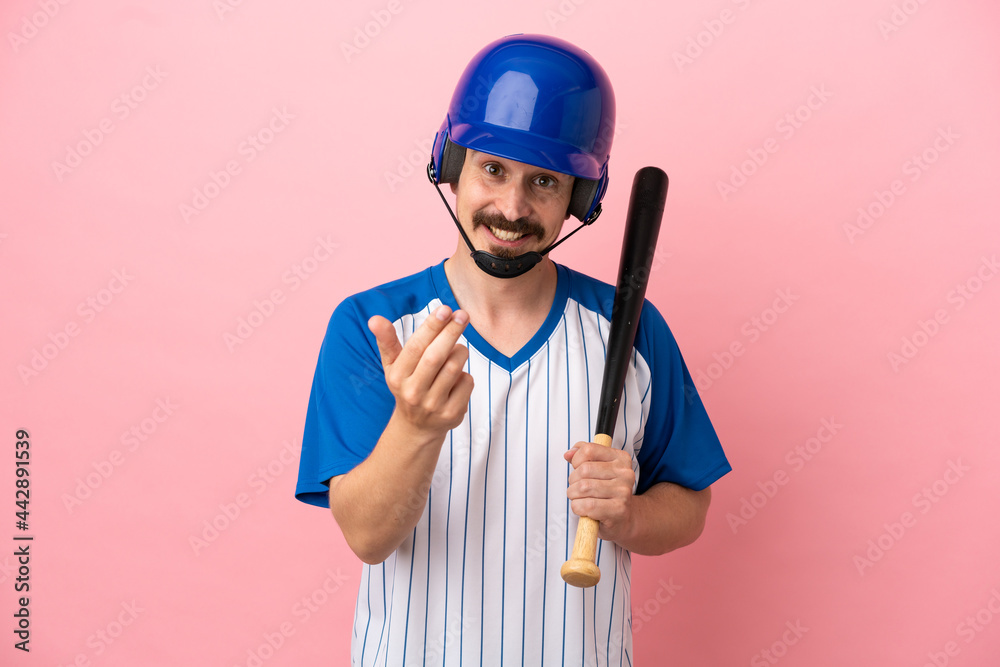 Young caucasian man playing baseball isolated on pink background inviting to come with hand. Happy that you came