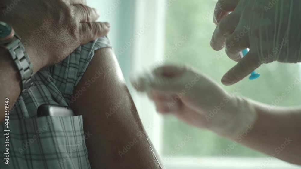 A female doctor vaccinates an elderly man against the coronavirus.