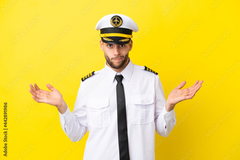 Airplane caucasian pilot isolated on yellow background having doubts while raising hands