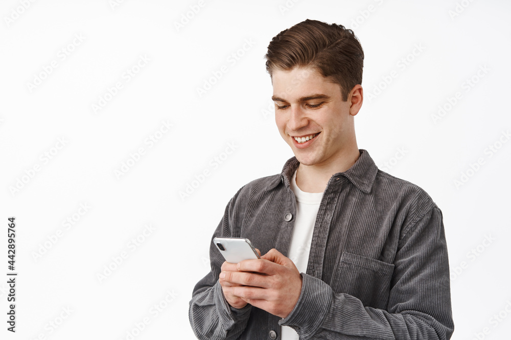 Close up portrait of young man, college student texting on phone, chat with friend on smartphone social media app, using application, standing over white background Close up portrait of young man, college student texting on phone, chat with friend on smartphone social media app, using application, standing over white background