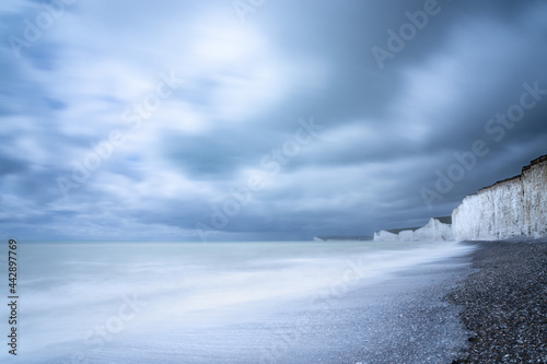 Seven Sisters white chalk cliffs taken from Birling Gap looking towards Seaford, Newhaven, Brighton with a swirling blue and white sky and a long exposure with a white wave incoming. photo