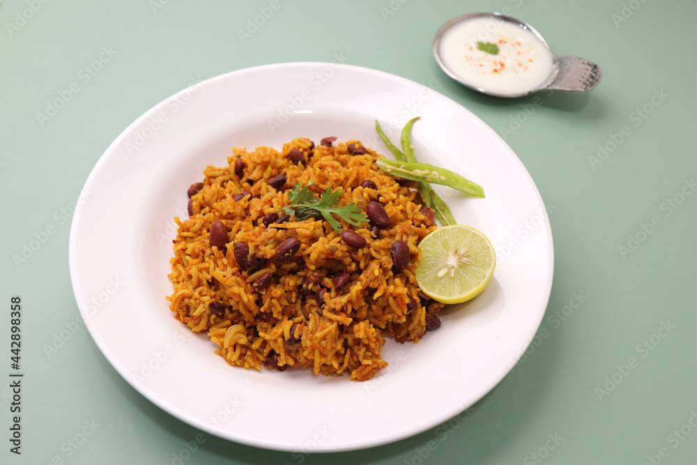 Indian cuisine - Kidney Beans Biryani, Rajma Pulao. Garnished with chopped coriander, and lemon wedges. Rajma biryani served with dahi. Along with copy space. Rajma Chawal flatlay. Indian cuisine - Kidney Beans Biryani, Rajma Pulao. Garnished with chopped coriander, and lemon wedges. Rajma biryani served with dahi. Along with copy space. Rajma Chawal flatlay.