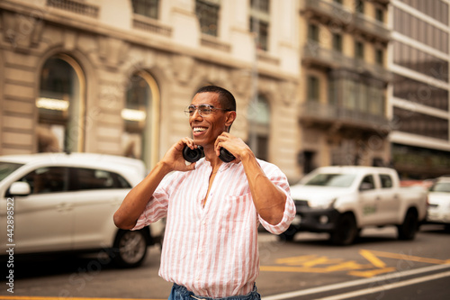 Cheerful guy listening the music with the headphones. Young african man outdoors © JustLife