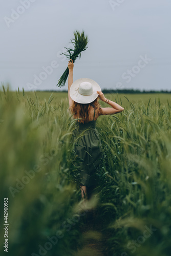 Young woman in a hat walking in a wheat field, enjoys life and summer. Wheat field.Healthy lifestyle Concept