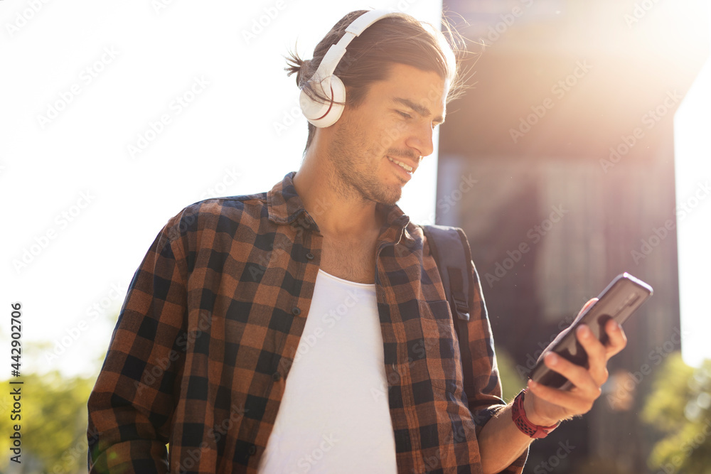 Young smiling man with headphones outdoors. Handsome man listening the music. Young smiling man with headphones outdoors. Handsome man listening the music.